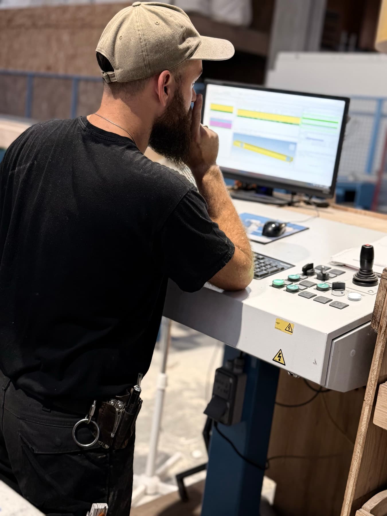 Jérémie, charpentier et Compagnon du Devoir, vu de dos à son poste de travail dans l'atelier