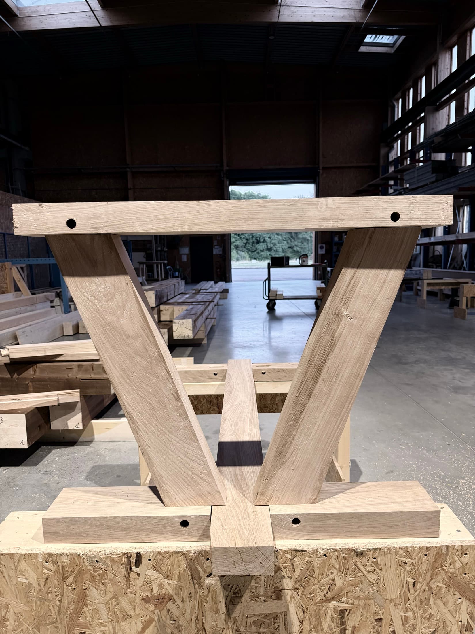 Pied de table en V en chêne massif dressé dans l'atelier